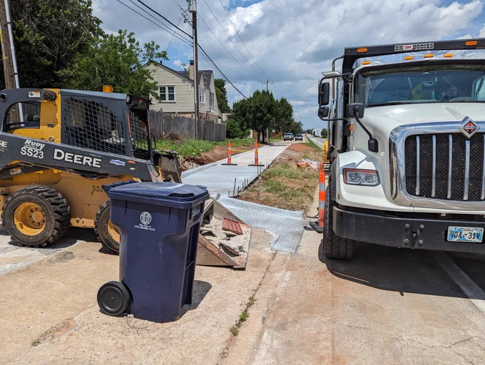 Photo looking back at where the new graded sidewalk meets with the bike lane. Construction vehicles and cones are obstructing them as they were still a work in progress.