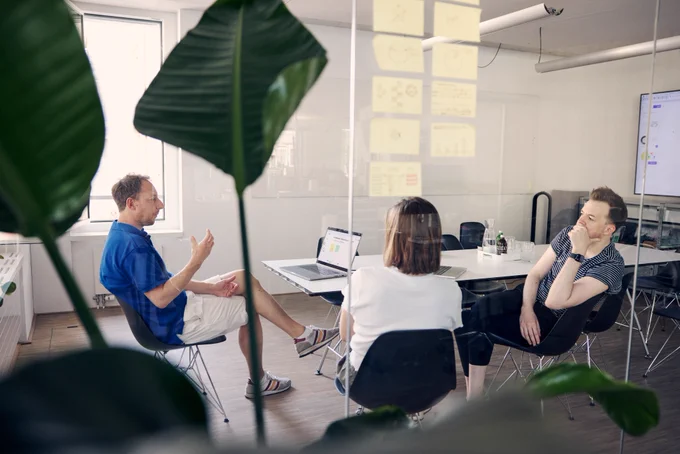 Our team members Christian, Michela, and Jan sitting and discussing in a meeting room in our studio.