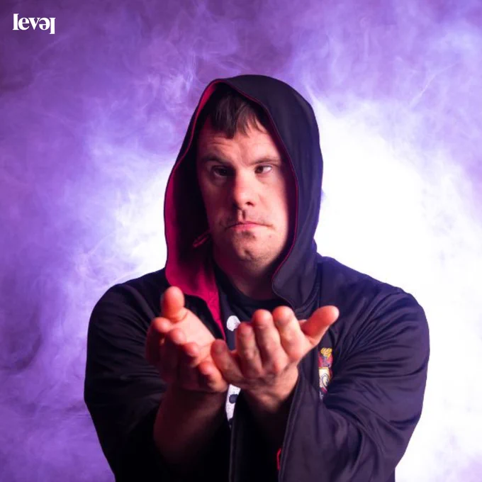 A person wearing a hooded top with purple smoke in the background.