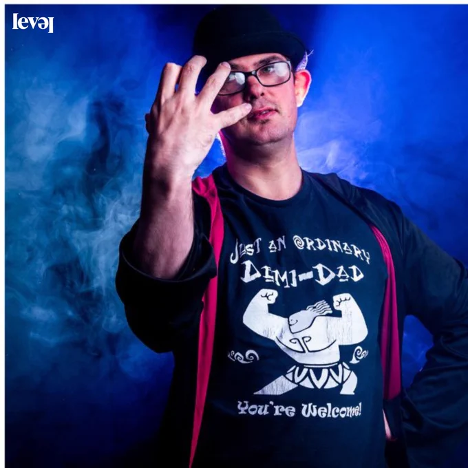 A person dressed in a wizards cloak with blue smoke in the background.