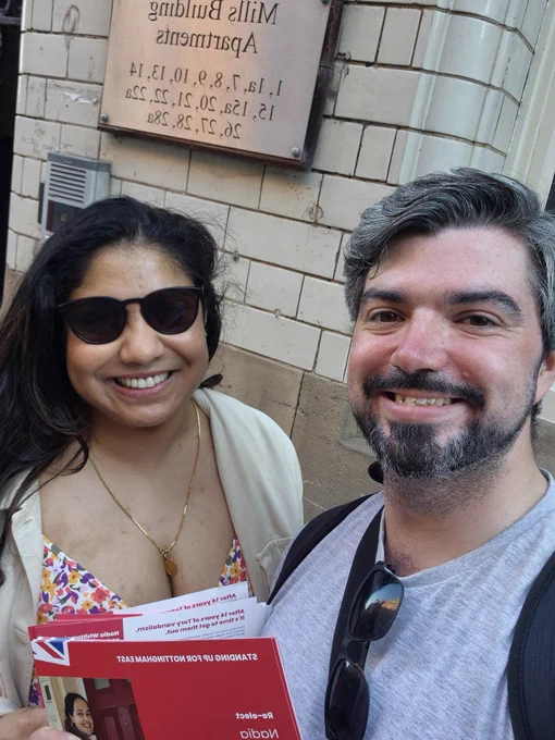 Matt and Sanya standing in front of the Mills Building on Plumptre Street. They're both holding leaflets for Nadia Whittome
