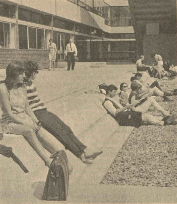 A black and white image showing students sitting outside at Warwick's Gibbet Hill campus. Behind them is the Maths Institute building. 