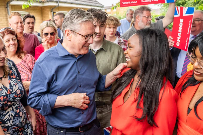 A photograph of Keir chatting to a woman in a group of people at an event