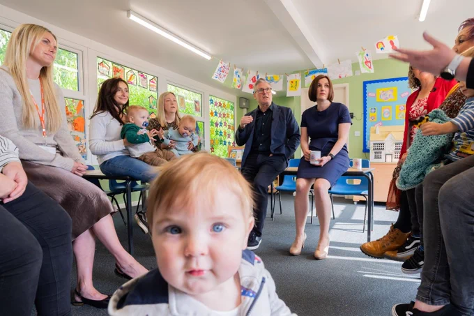 A photograph of Keir Starmer and Bridget Phillipson in a classroom with a baby in the foreground. 