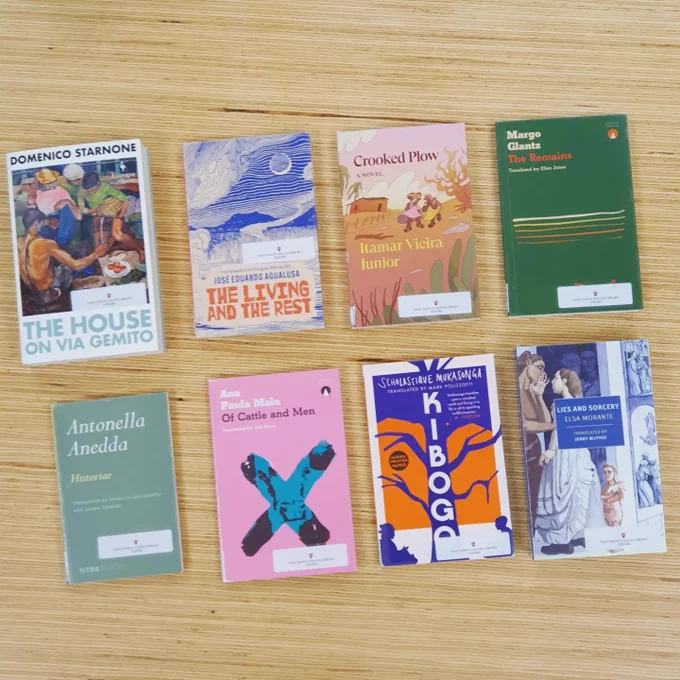 The eight books shortlisted for the Oxford Weidenfeld prize laid out on a wooden background. The books are: 
The Living and the Rest by José Eduardo Agualusa, translated from the Portuguese (Angola) by Daniel Hahn (MacLehose)
Historiae by Antonella Anedda, translated from the Italian by Patrizio Ceccagnoli and Susan Stewart (New York Review of Books)
The Remains by Margo Glantz, translated from the Spanish (Mexico) by Ellen Jones (Charco Press)
Of Cattle and Men by Ana Paula Maia, translated from the Portuguese (Brazil) by Zoë Perry (Charco Press)
Lies and Sorcery by Elsa Morante, translated from the Italian by Jenny McPhee (New York Review of Books)
Kibogo by Scholastique Mukasonga, translated from the French (Rwanda) by Mark Polizzotti (Daunt Books)
The House on Via Gemito by Domenico Starnone, translated from the Italian by Oonagh Stransky (Europa Editions)
Crooked Plow by Itamar Vieira Junior, translated from the Portuguese (Brazil) by Johnny Lorenz (Verso Books)