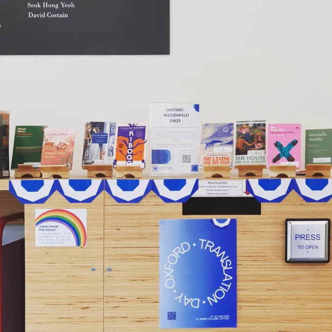A display with the eight shortlisted books sitting on wooden book stands on top of our book-drop. The book-drop is decorated with the OCCT logo and a poster advertising Oxford Translation Day