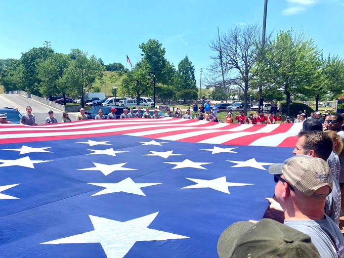 Law enforcement personnel stretch out an American flag. 