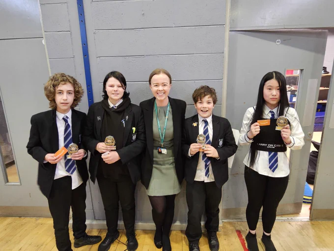 Image shows four pupils holding their awards and their class teacher