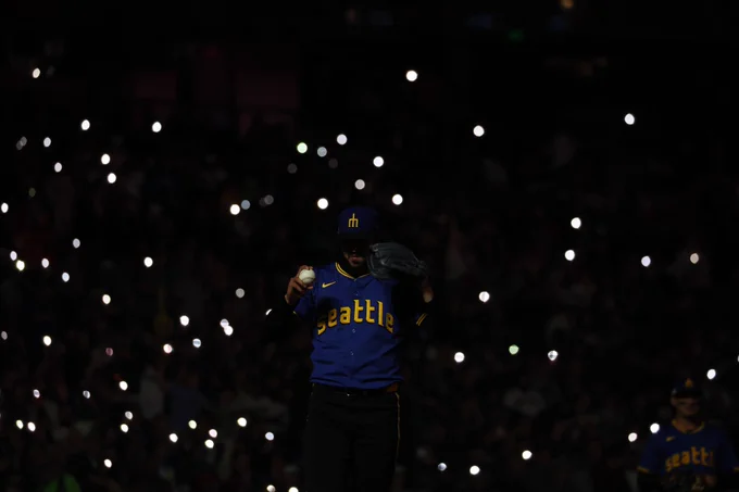 Andres Muñoz stands on the mound as the interior of T-Mobile Park goes dark. His silhouette is illuminated by twinkling lights all around him. (Photo: Mollie Handkins/MLB)