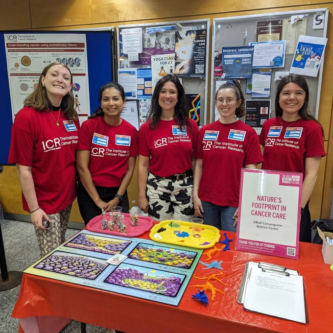 The five members of the ICR team stood behind the stall at the festival. They're all smiling and wearing ICR-branded t-shirts. There are colourful activities on the table.
