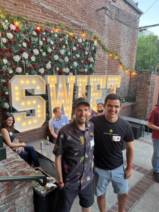 Ne and Alex in front of a Swift sign