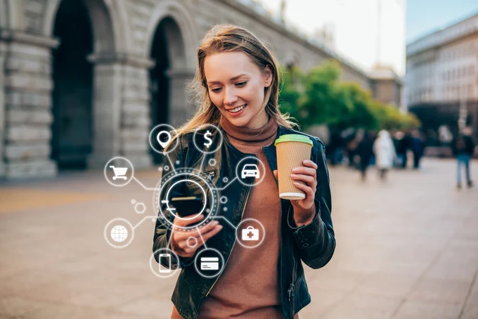 A person walking in a busy urban area, holding a coffee cup and interacting with augmented reality icons related to social media and technology floating around them.