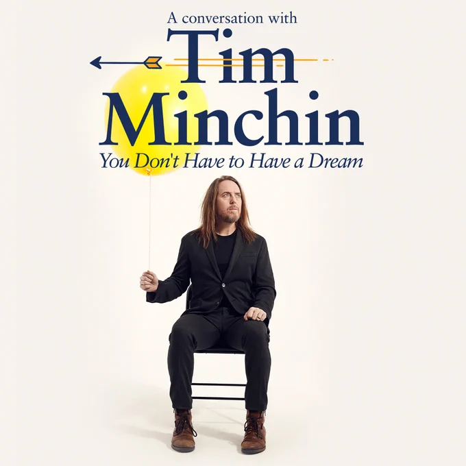Man sat on a chair holding a balloon. Text reads A Conversation with Tim Minchin You Don't Have to Have a Dream