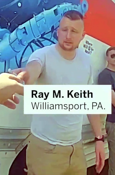 A video still of bodycam footage, edited by the Boston Globe, depicting Keith Mathew Ray of Williamsport PA. He is being handed his ID by a member of the Massachusetts State Police, after the UHaul he was traveling in was pulled over, after Patriot Front's march through Boston MA during July 2022. His name and city of residence have been superimposed in a video overlay underneath his face.