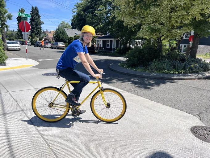 claire wearing a yellow helmet on an all-yellow fixie bicycle