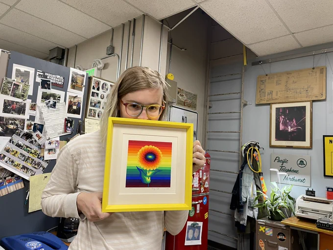 claire holding a brightly yellow framed Ay-Ō screenprint