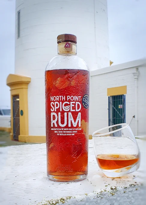Bottle of North Point Spiced Rum in front of the tower of Noss Head Lighthouse