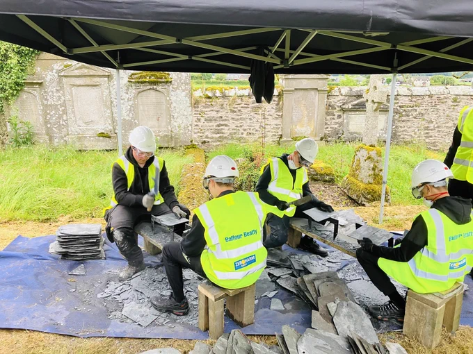 A group of young people wearing high-visibility jackets are working with slate