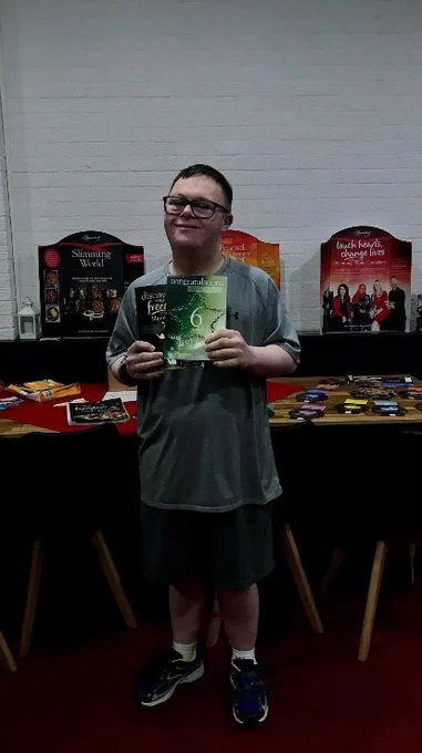lewis holding his swimming world ceriticate and smiling