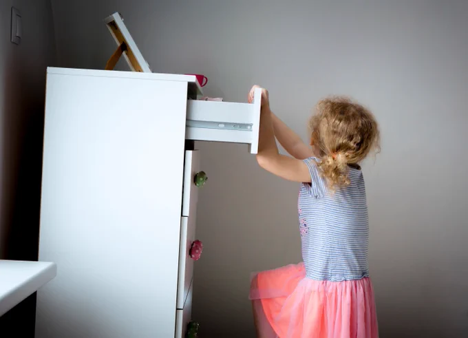 Child climbing on a chest of drawers which is about to fall