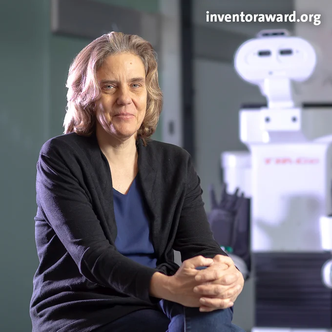 Photo de Cordelia Schmid prise dans la salle de robotique d'Inria avec, en arrière plan, le robot Tiago.
