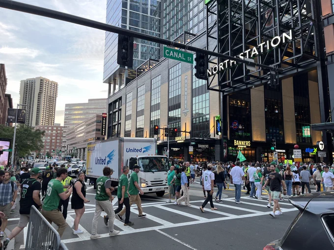 Pedestrians, many dressed in green, cross congested Canal Street in front of North Station.