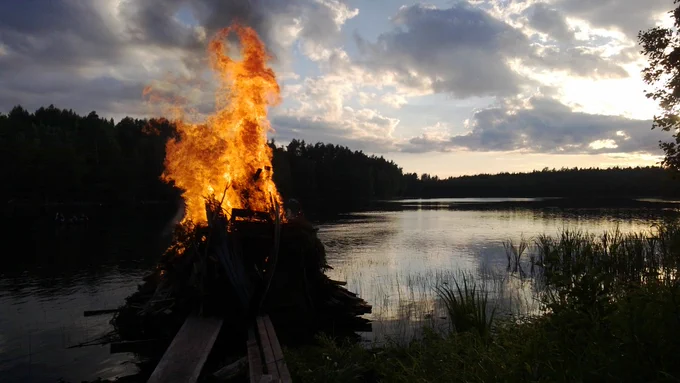 Palava kokko pimeässä kesäillassa järven rannalla.