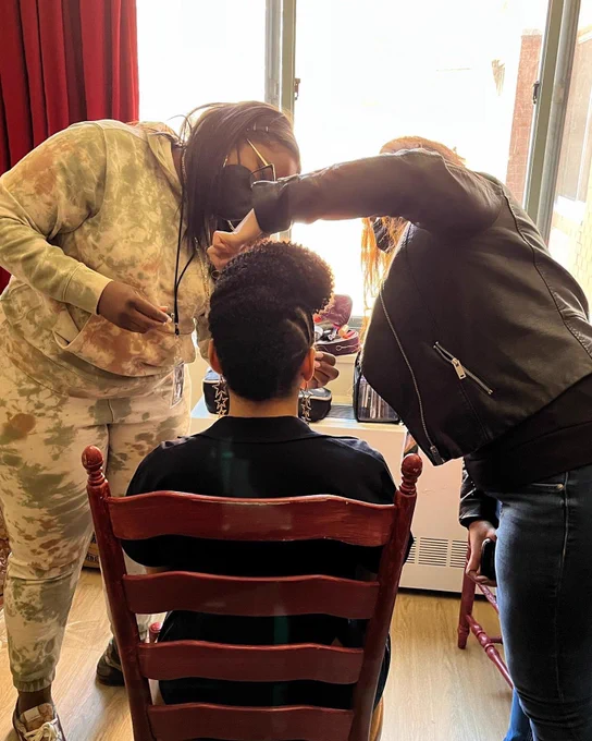 Shot from behind of moiya sitting in a chair to get her hair and makeup done for a video shoot.