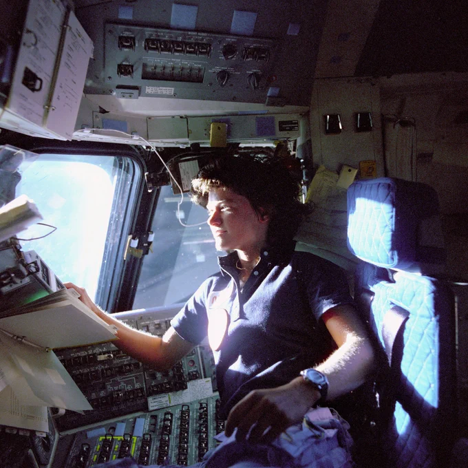 Astronaut Sally K. Ride, mission specialist on the STS-7 space shuttle mission, monitors control panels from the pilot's chair on the Flight Deck. Floating in front of her is a flight procedures notebook. Credit: NASA