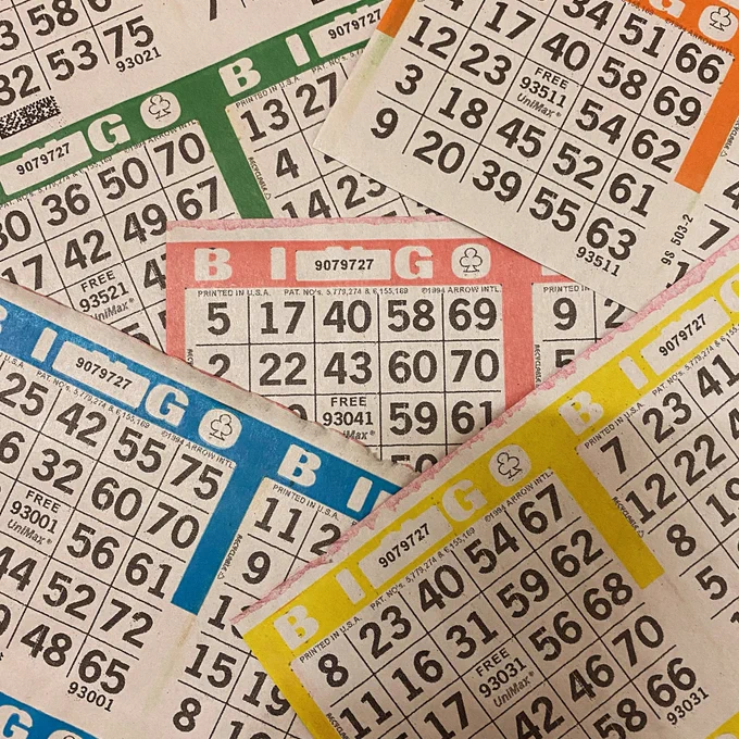 a number of different colored bingo cards are arranged chaotically yet artfully on a table are photographed