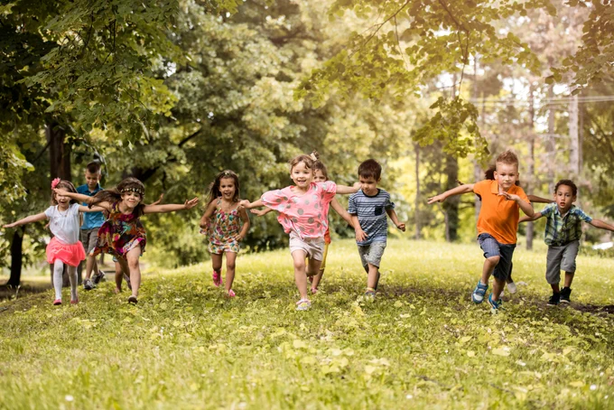 A group of children running across grass on a sunny day.
