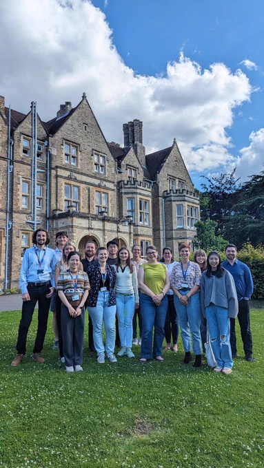 A lab group standing and smiling in front of St Hilda's College, Oxford.