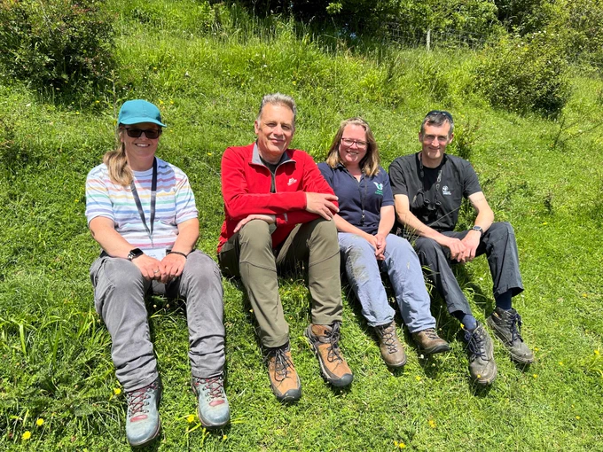 Sarah from the Royal Entomological Society, Chris Packham, Caroline from Butterfly Conservation and Mark from Somerset Wildlife Trust sat together on a grassy bank, smiling at the camera