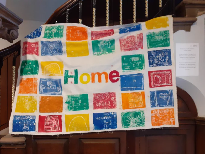 A banner with block colour prints on it and the word 'home' hangs on some stairs.