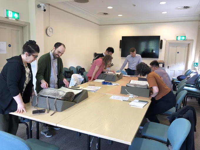 Image showing a group of people gathered around a table to examine historic books and documents. 