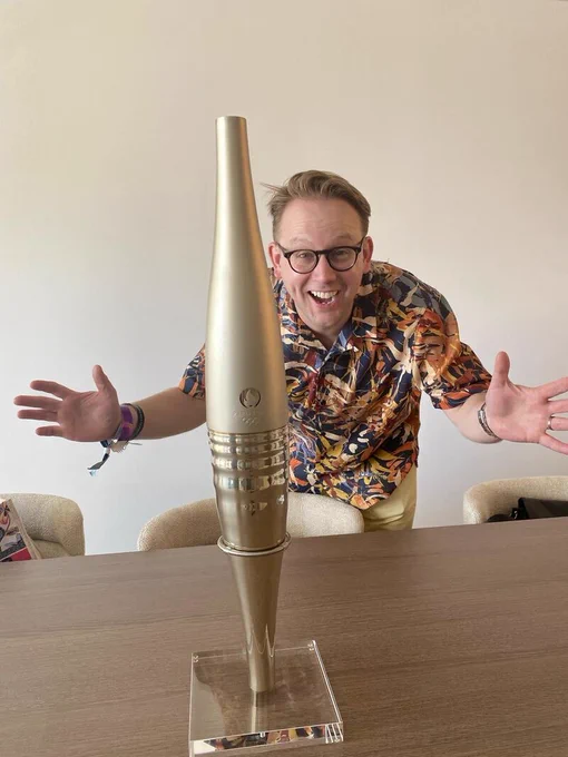 Simon stands behind a torch, delighted with it