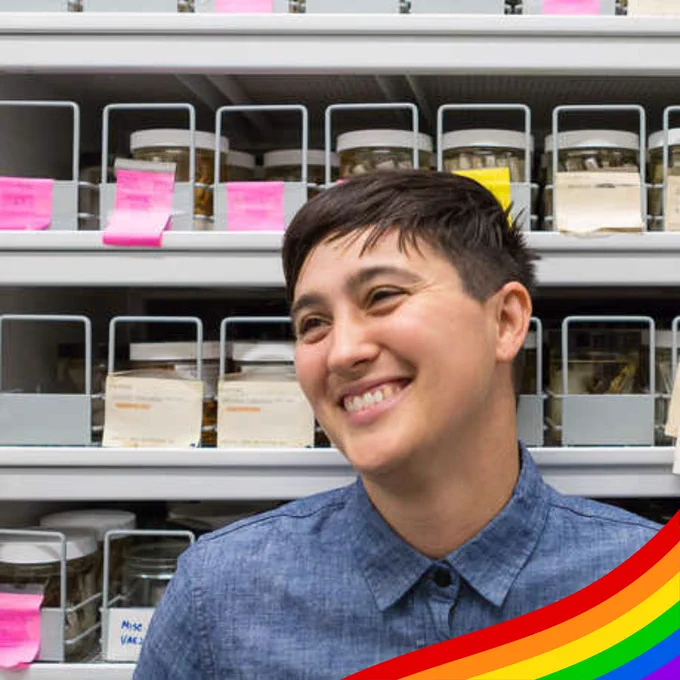 Lauren Esposito smiles in front of shelves stocked with labeled jars. A rainbow decorates the bottom right hand corner of the image.
