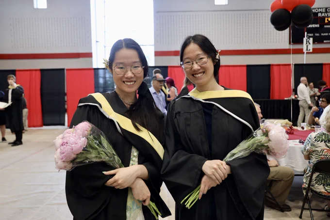 Graduating twins smile together after the ceremony.