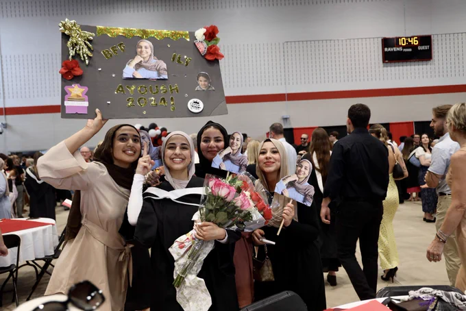 Friends celebrate their grad with a poster that says “bff” and “ily” with decor after the ceremony.