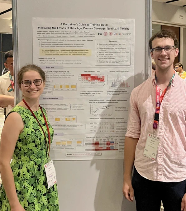 two paper authors standing next to a poster