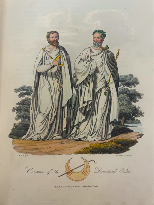 colour plate from a book showing two bearded men wearing long flowing white gowns. one is wearing leaves in his hair and carrying a golden staff. the other is carrying a golden crescent moon. It is entitled Costume of the Druidical Order.