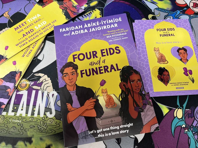 A copy of the book “Four Eids and a Funeral” on a desk with promotional bookmarks and sticker sheets next to it.