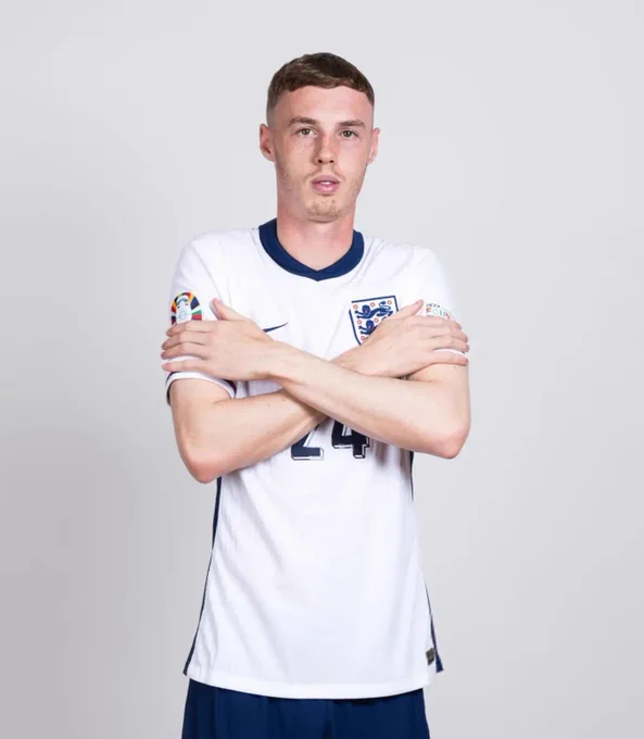 Cole Palmer with his arms crossed over his chest, looking cold.