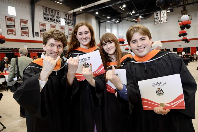 Students posing with their degrees, holding up their pinkies showing their engineering ring.