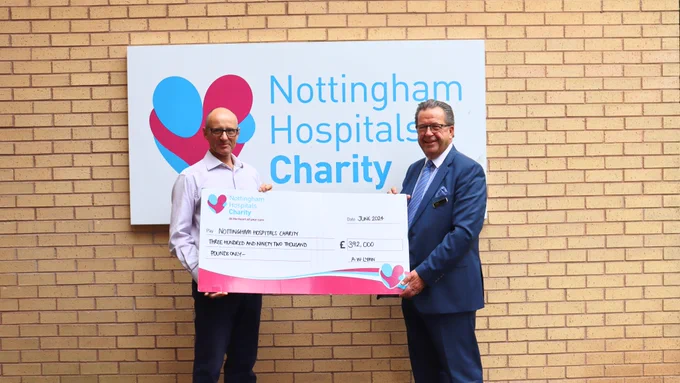 Nigel from Nottingham Hospitals Charity stands with Nigel from A.W. Lymn and they hold a big cheque with the total amount on it. 