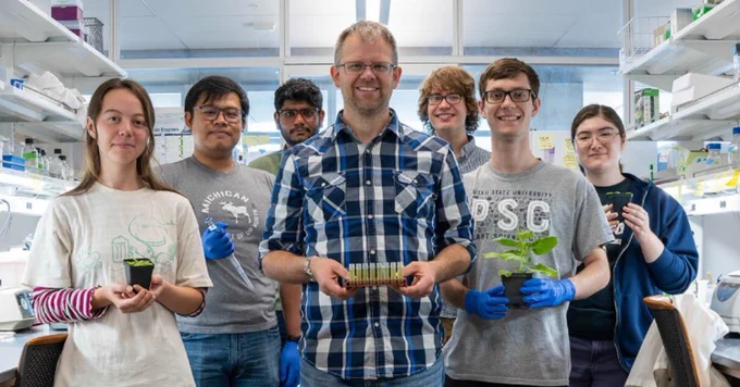 Peter Lundquist standing in his lab with his research assistants and graduate students.