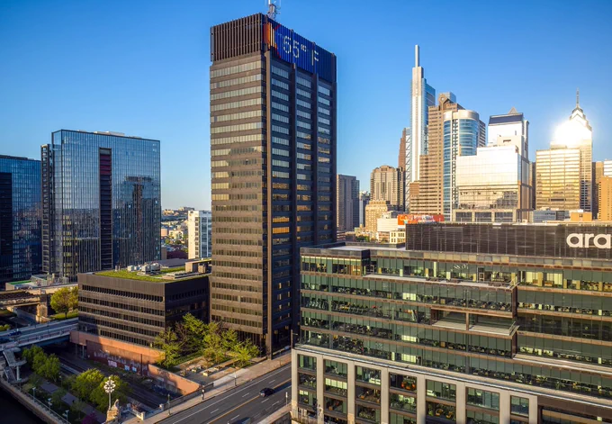 A cityscape photo of modern high-rise office buildings in a downtown area under a clear blue sky.