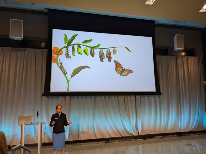 Sydney Shaffer in front of a slide showing the stages of butterfly development