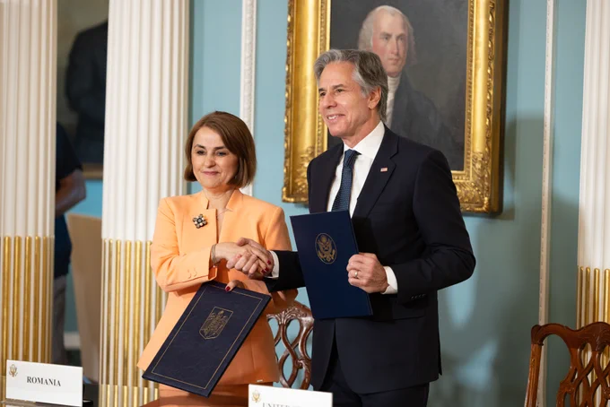 Secretary Blinken and Romanian Foreign Minister Luminta-Teodora Odobescu shaking hands while holding copies of a memorandum of understanding that they just signed with at the Department of State in Washington. (Official State Department photo by Chuck Kennedy)