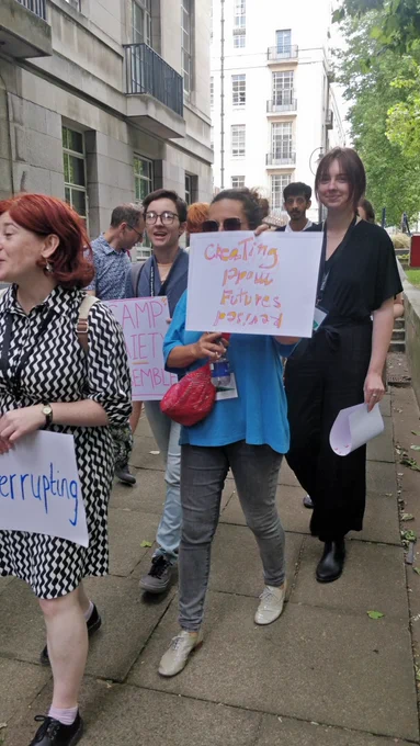 A group of people walking holding up handwritten signs